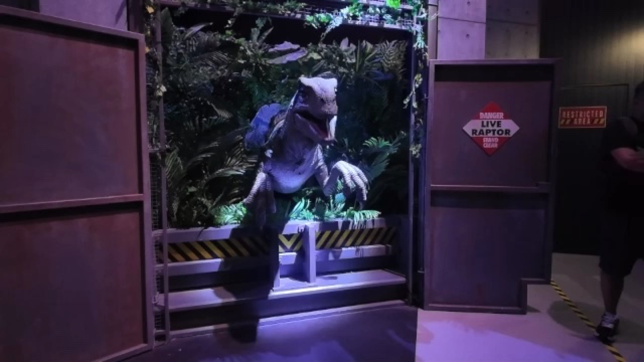 檻の中から現れたラプターと解説スタッフ