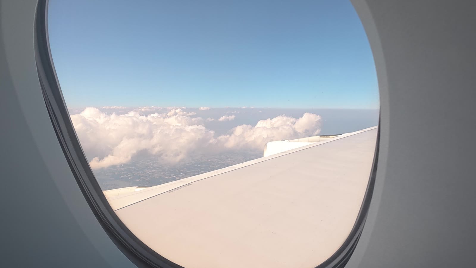 機内の窓から見える主翼と雲